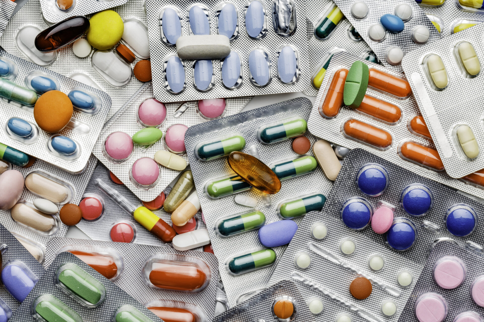 Health themes. Background of a large group of assorted capsules, pills and blisters. Drug abuse.